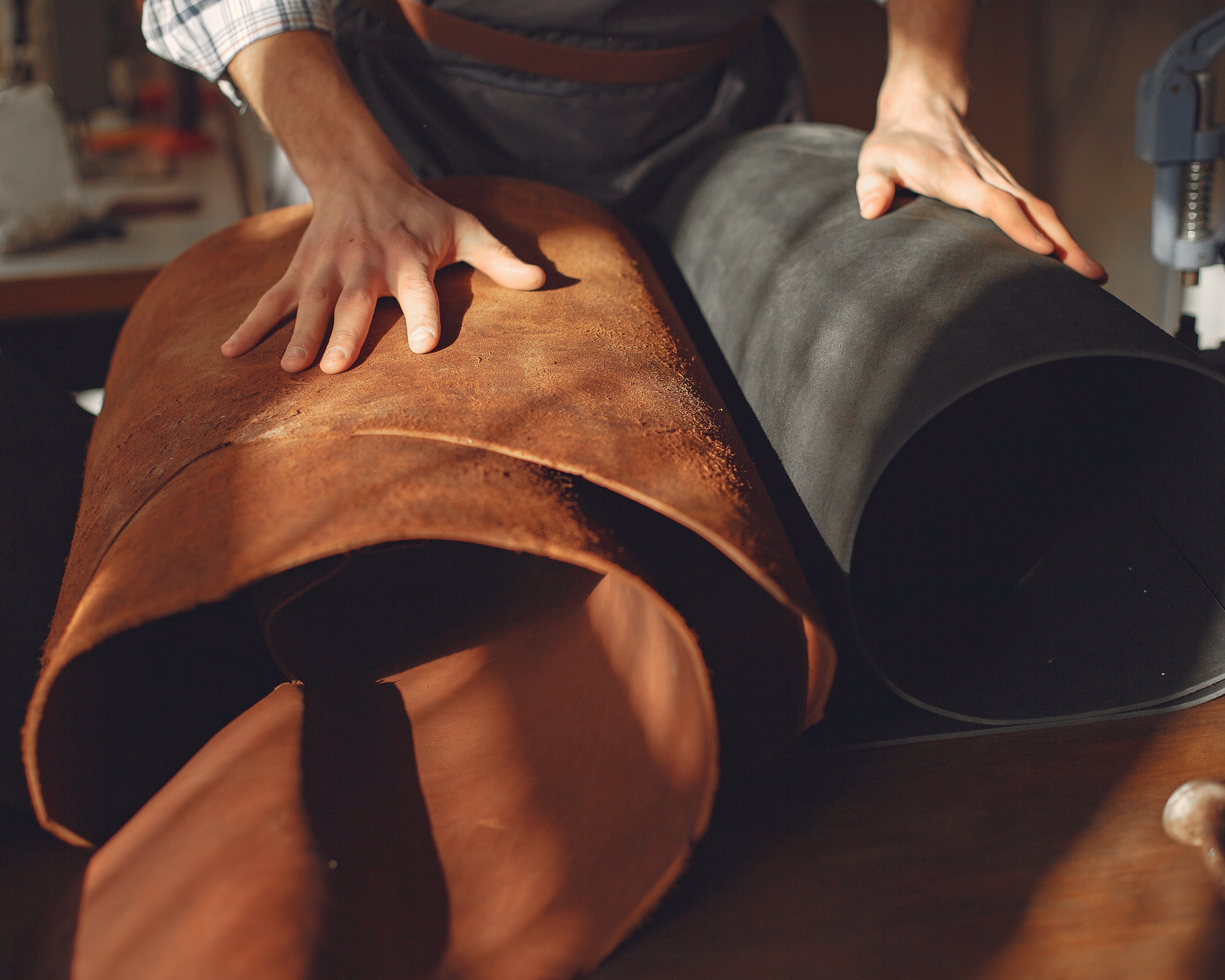 Person holding two rolls of leather in a workshop setting